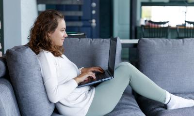 kvinde sidder i sofa med laptop på online undervisning